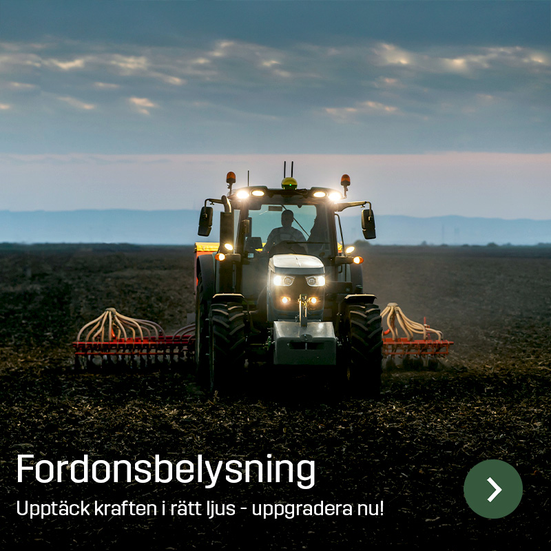 Traktor med tänd arbetsbelysning kör på åkermark med ett brett redskap bakom. Sagros fordonsbelysning används för att ge ljus runt lantbruksmaskiner vid arbete i fält.