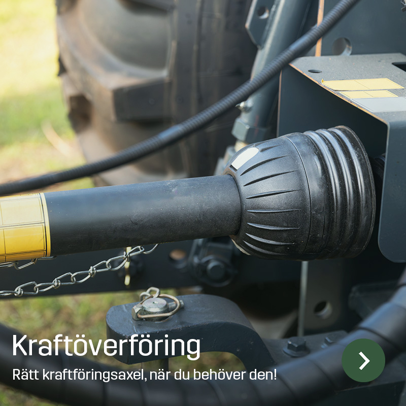 Närbild på kraftöverföringsaxel kopplad mellan traktor och redskap, med skyddskåpa och anslutning synlig. Sagros reservdel används för att överföra kraft mellan maskiner vid arbete i lantbruket.
